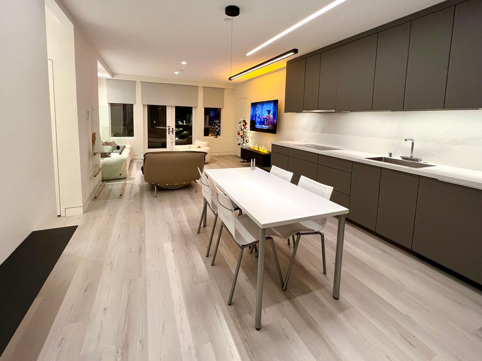 A panoramic shot showcasing the entire functional core of the home, emphasizing the intentional lack of visual clutter and the unifying elements like the linear light fixtures.