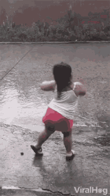 Cute girl enjoying the rainfall outside the house on the road