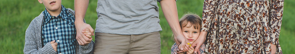 Parents holding hands with two small children.