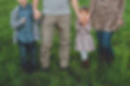 family holding hands while walking through a field