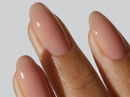 Close-up van elegante handen met een soft blush manicure in amandelvorm, afgewerkt met een subtiele glans en een natuurlijke, romantische uitstraling.