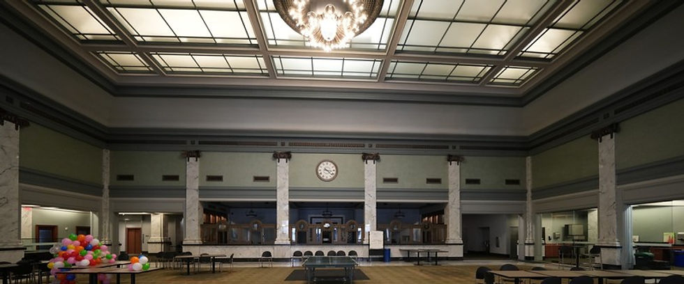 Modern interior of the Commerce Trust Building lobby in Kansas City, showing the illuminated ceiling, chandelier, marble columns, and former teller windows.