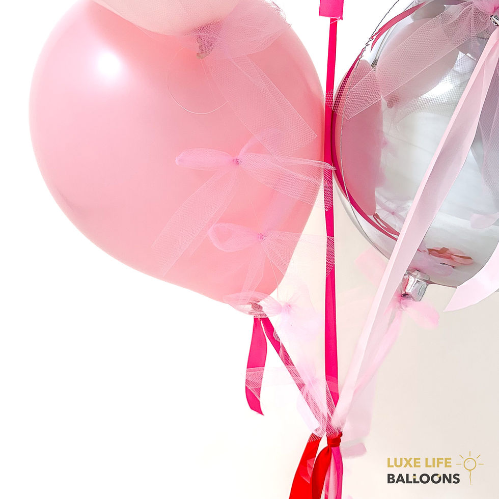 Pink and shinny silver balloons with pink bows, pink and red tassels hanging from Luxe Life Balloons Valentine's Day bouquet