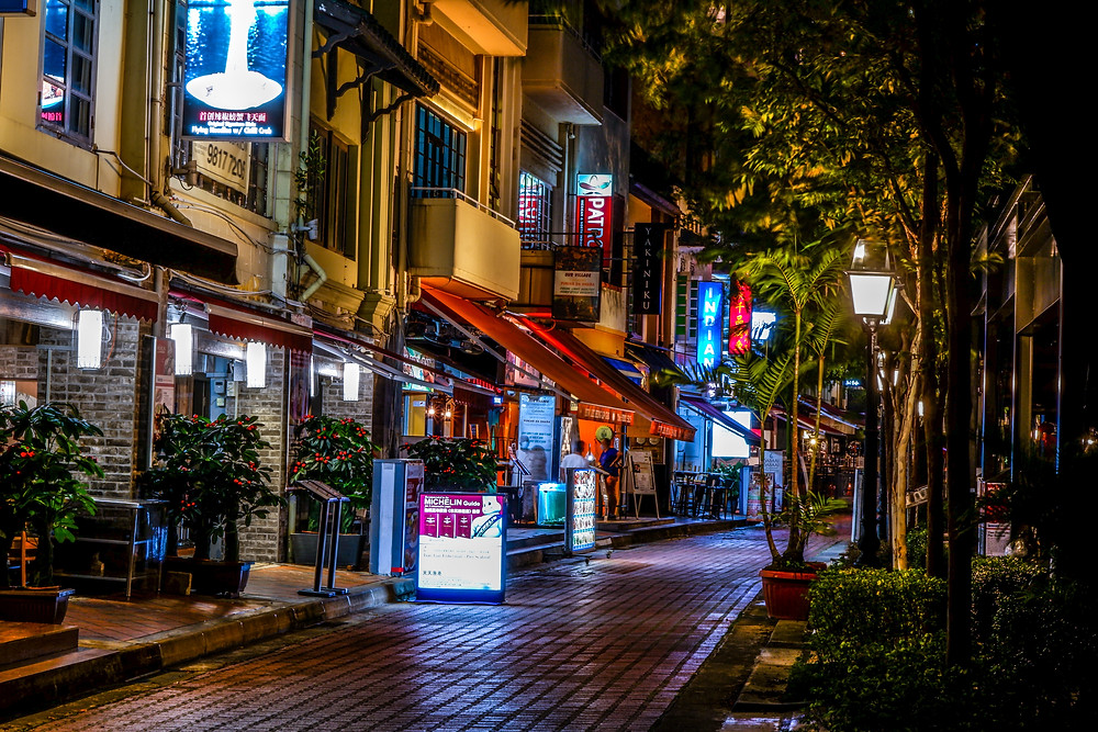 Colourful row of restaurants and bars along Boat Quay at night.