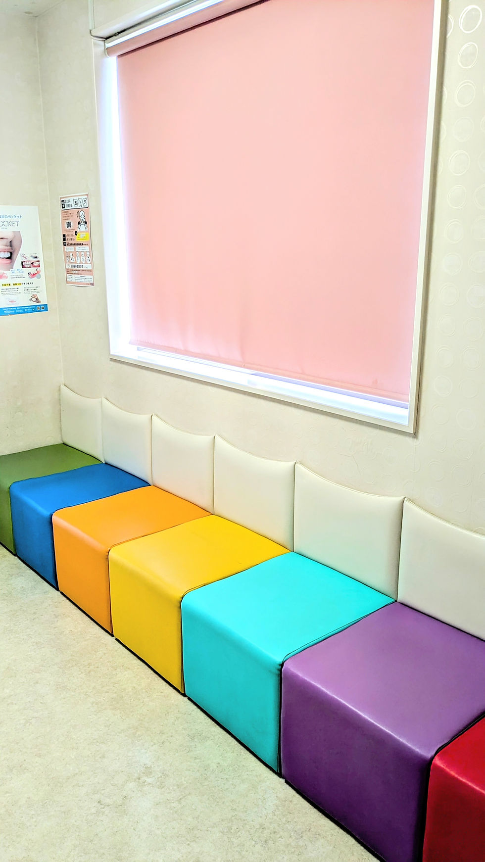 寝屋川市のおかだ歯科矯正歯科の待合室、子どもも安心できるカラフルで清潔なソファが並ぶ院内風景