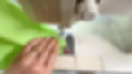 Hands using a sewing machine to sew a seam to box the corner of a pouch made of green jelly vinyl.