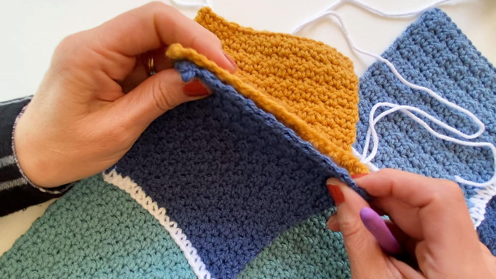 Hands showing how to hold the crocheted blocks to join them together to make a baby blanket.