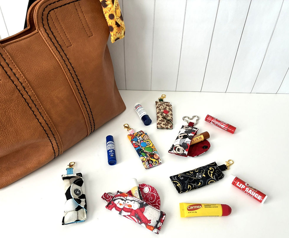 Brown handbag with sunflower lip balm holder and assorted lip balms in colorful holders on white surface. Vertical wood panel background.
