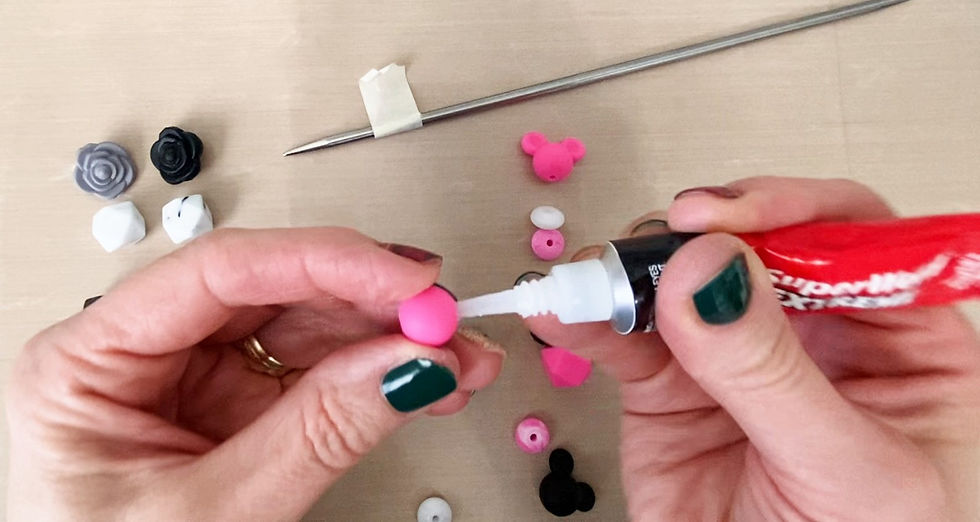 Hands putting glue on the inside of a pink silicone bead.