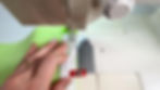 Hands using a sewing machine to sew a zipper to a piece of green jelly vinyl fabric.