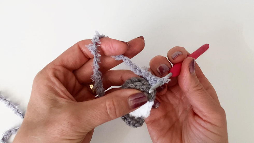 Hands crocheting two pieces together using Bernat Pipsqueak yarn.