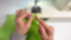 Hands holding a piece of green jelly vinyl and pointing to the place just next to the zipper tab to sew next.