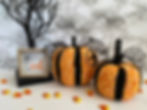 Two orange, yellow and black crocheted pumpkins with stems made from sticks for Halloween.
