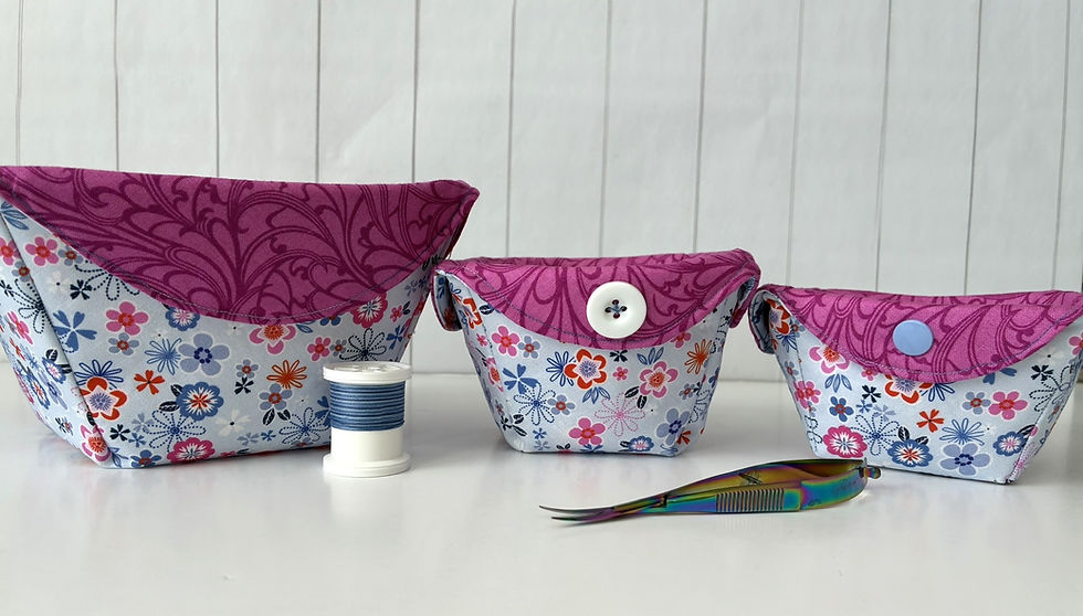 Three floral fabric pouches with purple tops, thread spool, and tweezers on white surface. Background features white paneling.