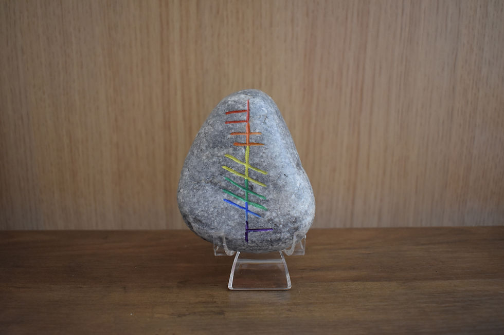 Stone with Ogham inscription in rainbow Pride colors.