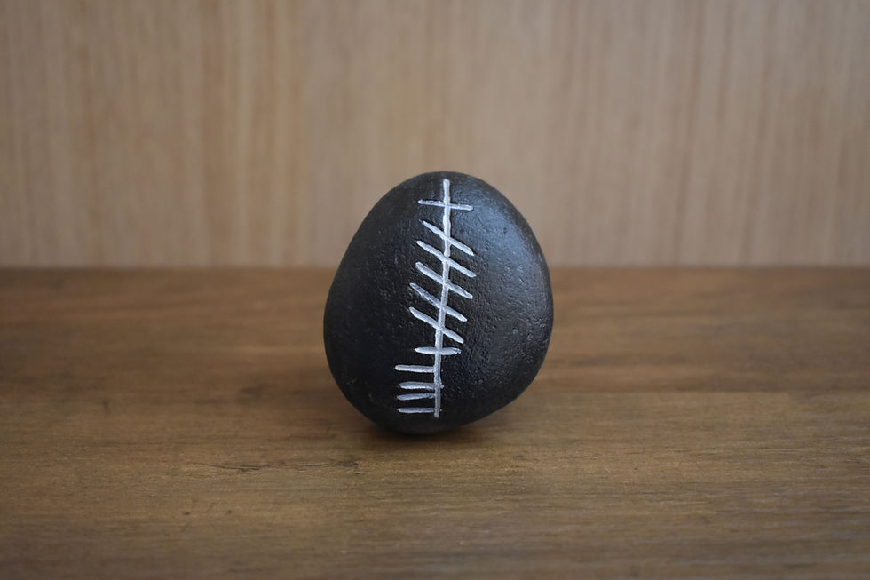 Painted black stone with white tally marks for Cara