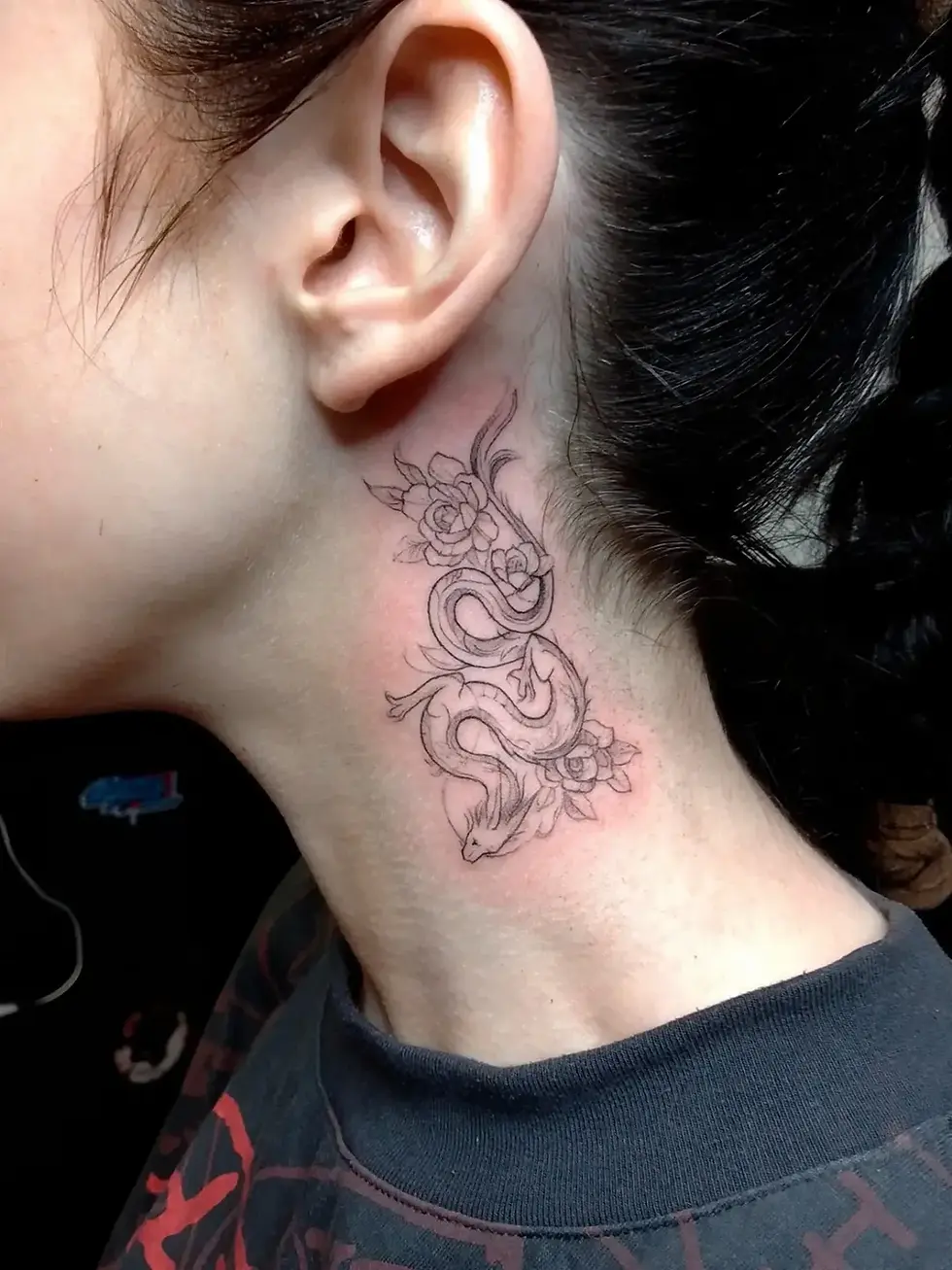 Close-up of a woman's neck and ear showing a delicate black snake-and-floral tattoo, with pink skin irritation against dark hair.