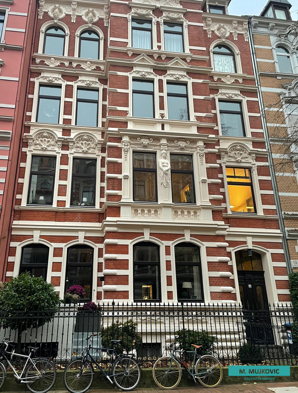 Denkmalgeschütztes Gebäude mit vielen Fenstern und einem Zaun, sorgfältig saniert und restauriert.