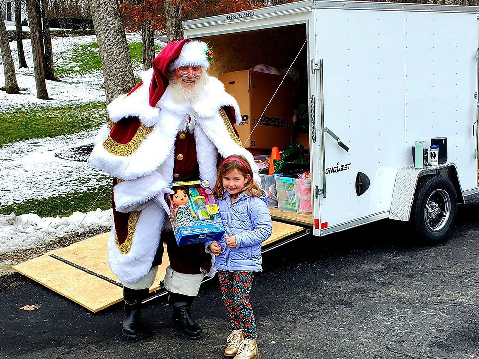Santa Claus distributing gifts from a donation trailer during a community holiday event