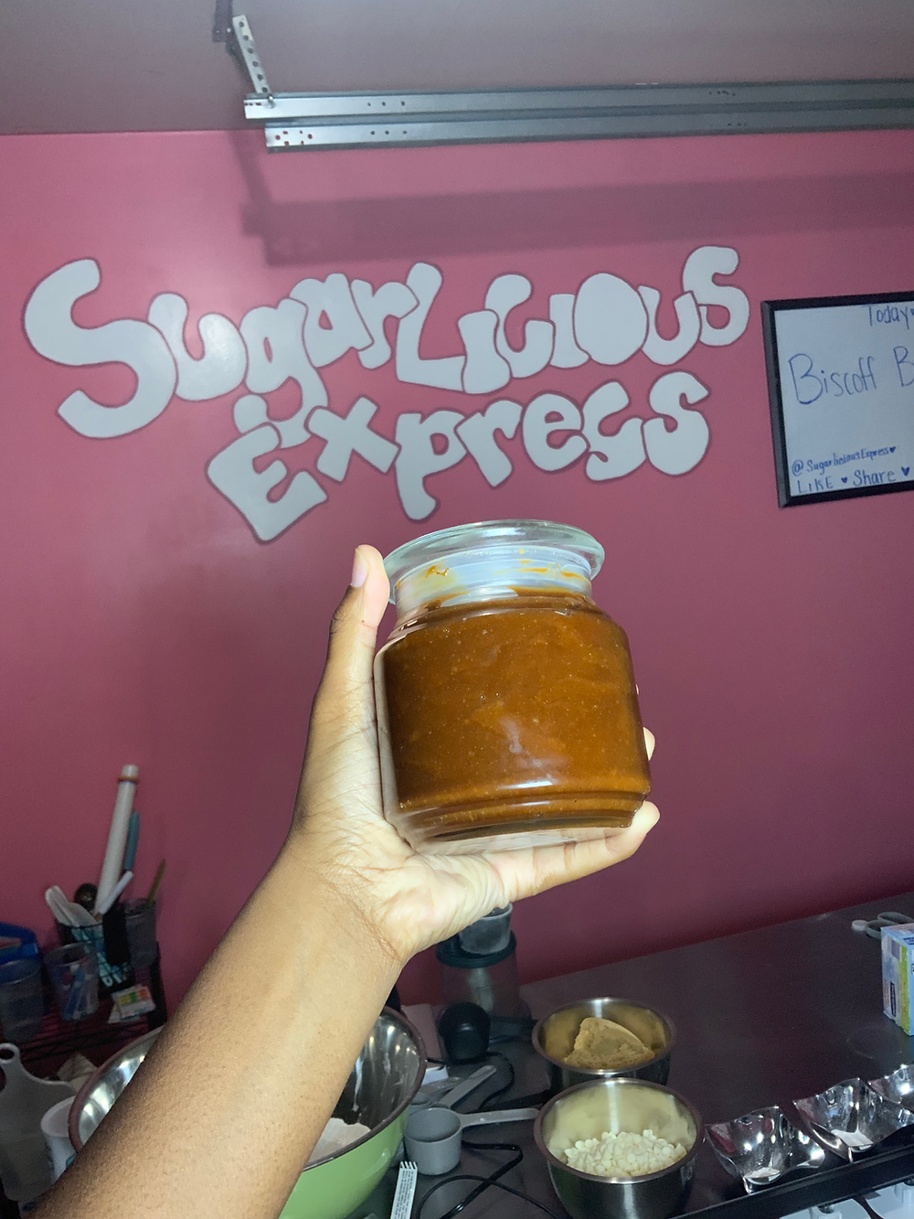 Hand holding jar of caramel spread at SugarLicious Express