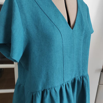 Robe 
Manches courtes, jupe évasée froncée, encolure en V délimitée par une bande centrale

Robe réalisée en lin