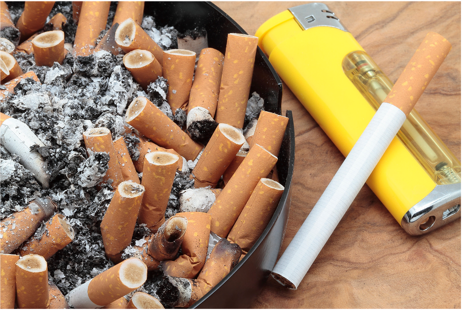 A really full ashtray of cigarette butts and ash, with a lighter and cigarette