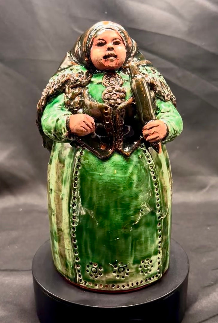 Miniatyrbilde: Keramikkfigur av kvinne i grønn kjole holder bok og rull.