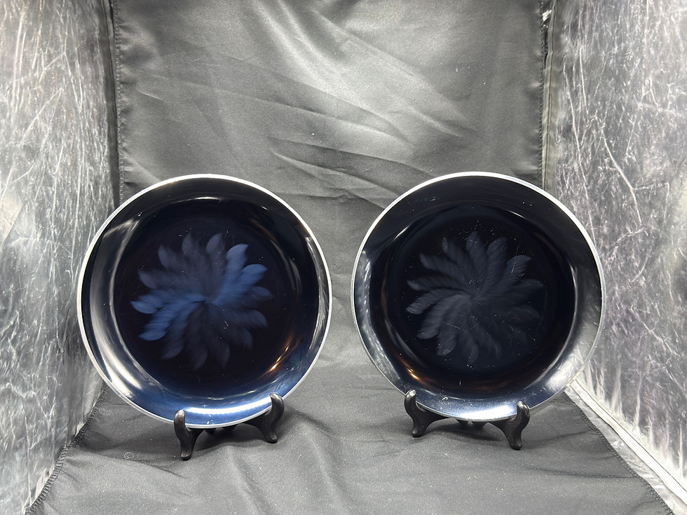 Miniatyrbilde: To mørkeblå tallerkener med hvitt spiralmønster på svarte holdere.