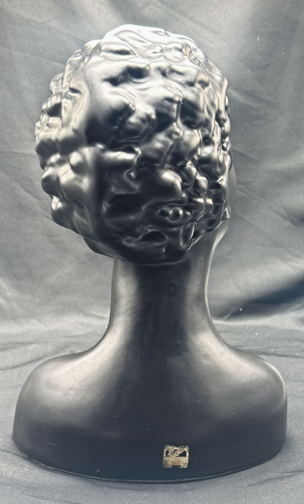 Miniatyrbilde: Svart byste med krøllete abstrakt hår, sett bakfra på mørk bakgrunn.