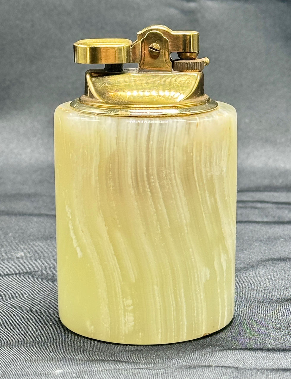 Miniatyrbilde: Vintage lighter med sylindrisk gul onyx-base, messingtopp, mørk bakgrunn.