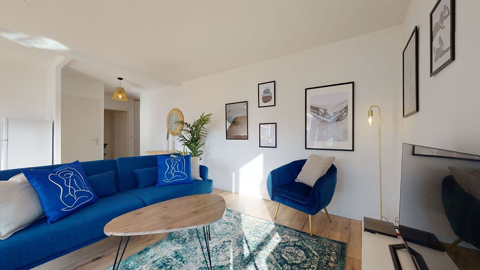 Aménager, meubler et décorer le salon d'une colocation : salon chaleureux avec canapé bleu vif, fauteuil assorti, tapis graphique et galerie de cadres muraux.