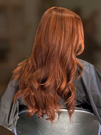 Rich copper hair color with long waves and dimensional red tones