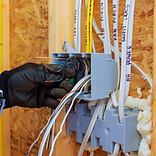 Electrician connects wires inside circuit box while renovating home, ensuring proper elect