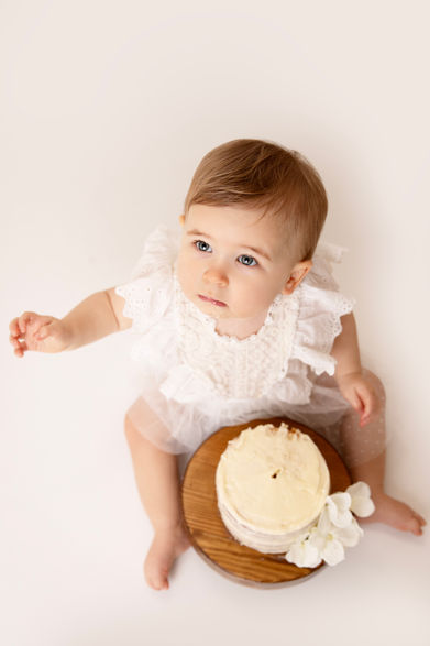 Child softly looking up while holding birthday cake, captured in a calm, candid moment.
