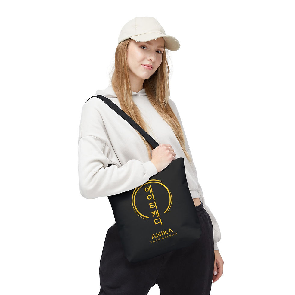 Woman holding black tote bag with gold circular Anika logo and Korean text