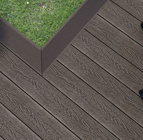 Dark wood composite decking showing edging, with some turf in shot