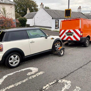 White Mini being towed by recovery van