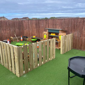 A small outdoor play area enclosed by wooden fencing
