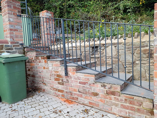 Black steel banister alongside curved stepped path