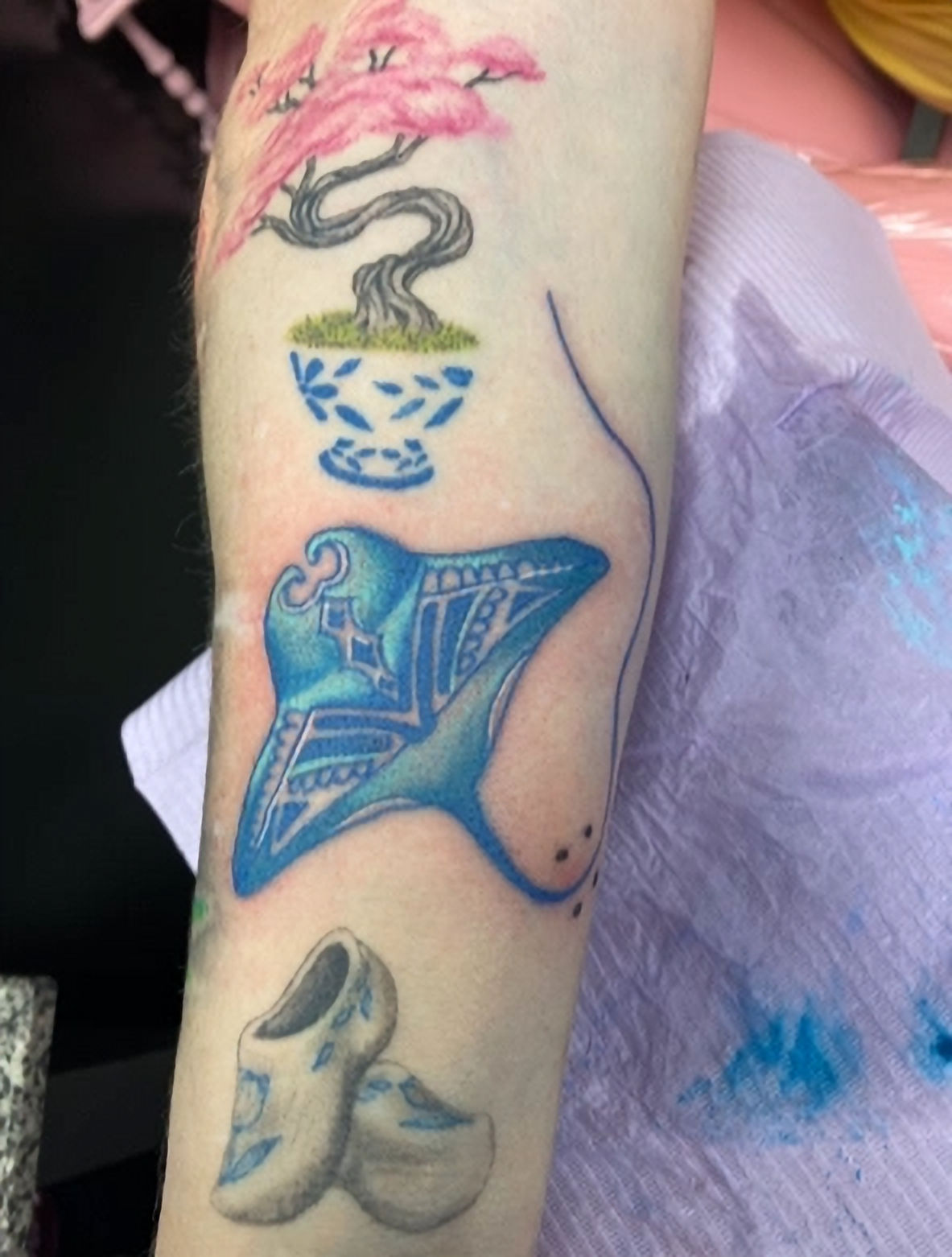Fine line botanical wildflower tattoo on forearm featuring delicate stem and leaf details