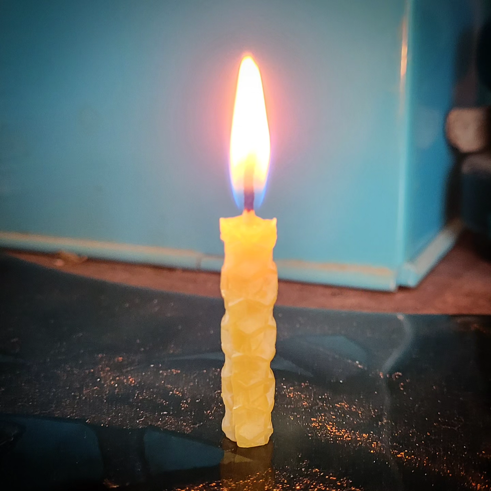 Tänt handrullat tårtljus av bivax med bikakemönster.