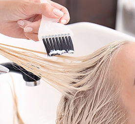 Ervaren kapper van Kapsalon @ Jo in Weurt verft het haar van een vrouwelijke klant in de salon aan de Kareldoormanstraat 1.