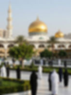 People walking towards a mosque with golden domes for Umrah travel.