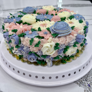 cake covered in pink purple and white buttercream flowers