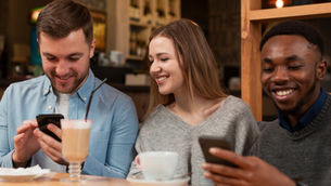 Amigos em uma cafeteria usando seu cashback do Albert no pagamento.