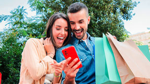 Um casal feliz com sacolas de compras na mão usando cashback.