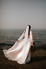 bride with veil and long sleeve wedding dress at the sea