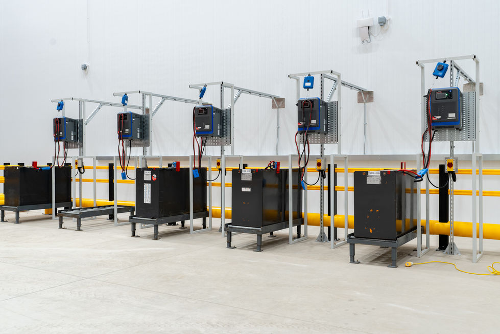 Battery charging stations installed along warehouse wall behind safety barriers