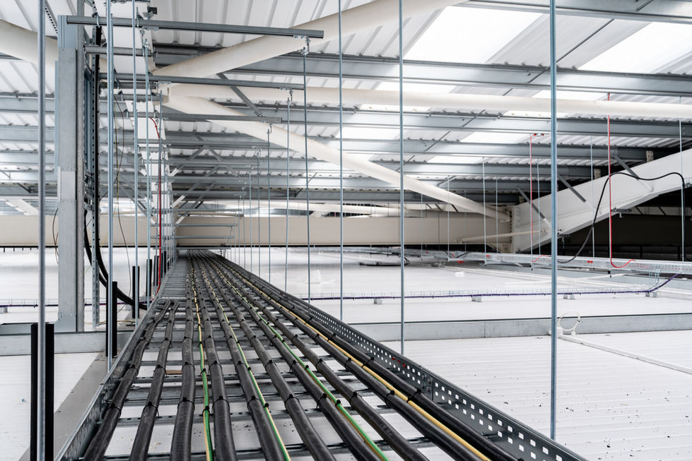 Suspended long cable containment run within warehouse roof void.