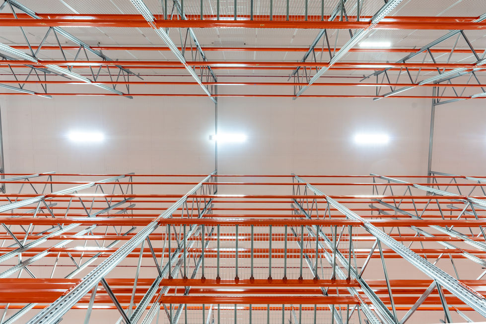 Upward view through warehouse racking structure toward illuminated ceiling